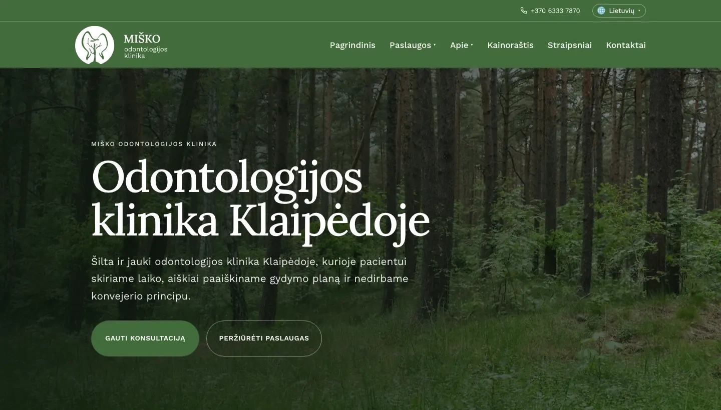 Lietuviškas „Miško klinikos“ pagrindinis puslapis su miško nuotrauka, odontologijos kliniką Klaipėdoje pristatančia antrašte ir atvertu kalbų meniu: „Lietuvių“, „English“ ir „Žemaitiu“
